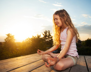 Girl meditating outdoors. Child practicing yoga